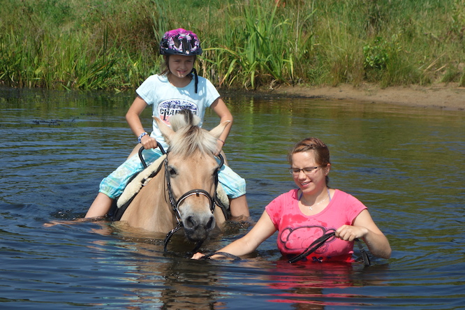 Anna schwimmt mit Lissla und einer kleinen Ponyreiterin im Teich