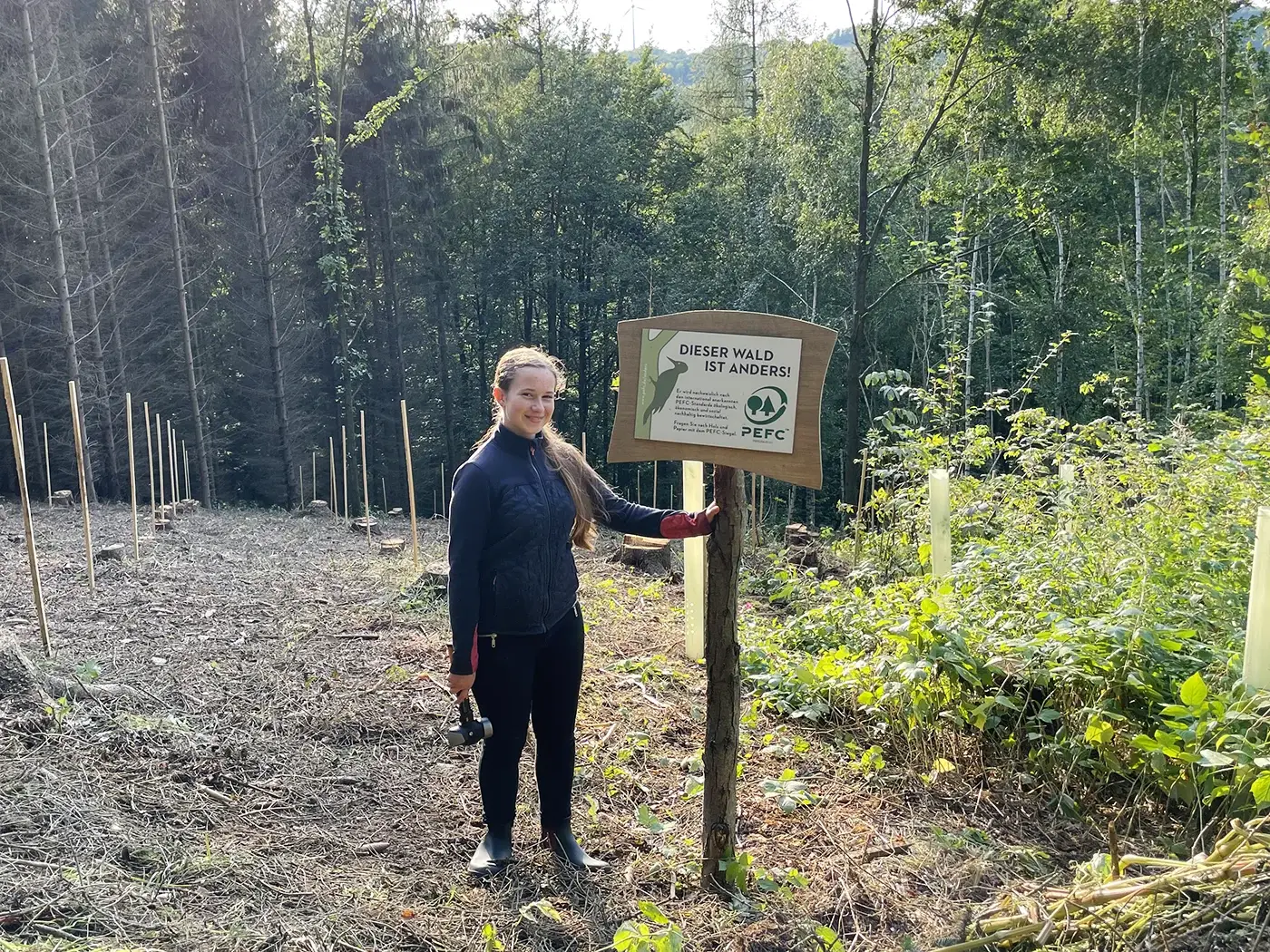 Lea befestigt ein Informatives Schild im Wald.