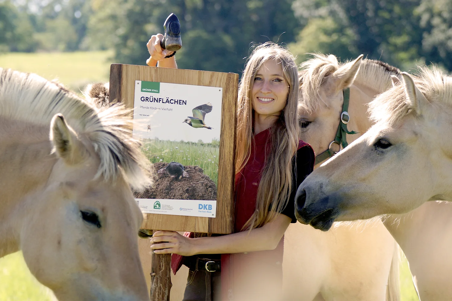 Anna-Karina Kemper steht mit Fjordpferden um das Schild: Pferde fördern Vielfalt.