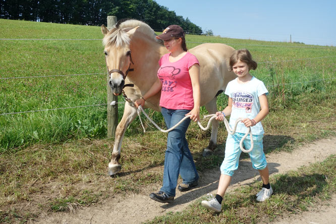 FÖJlerin Anna begleitet die Kinder dabei, die Pferde von der Weide zu holen