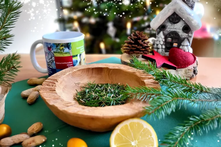 Fichtennadeln in einer Holzschale mit Fichtenzweigen und Teetasse.