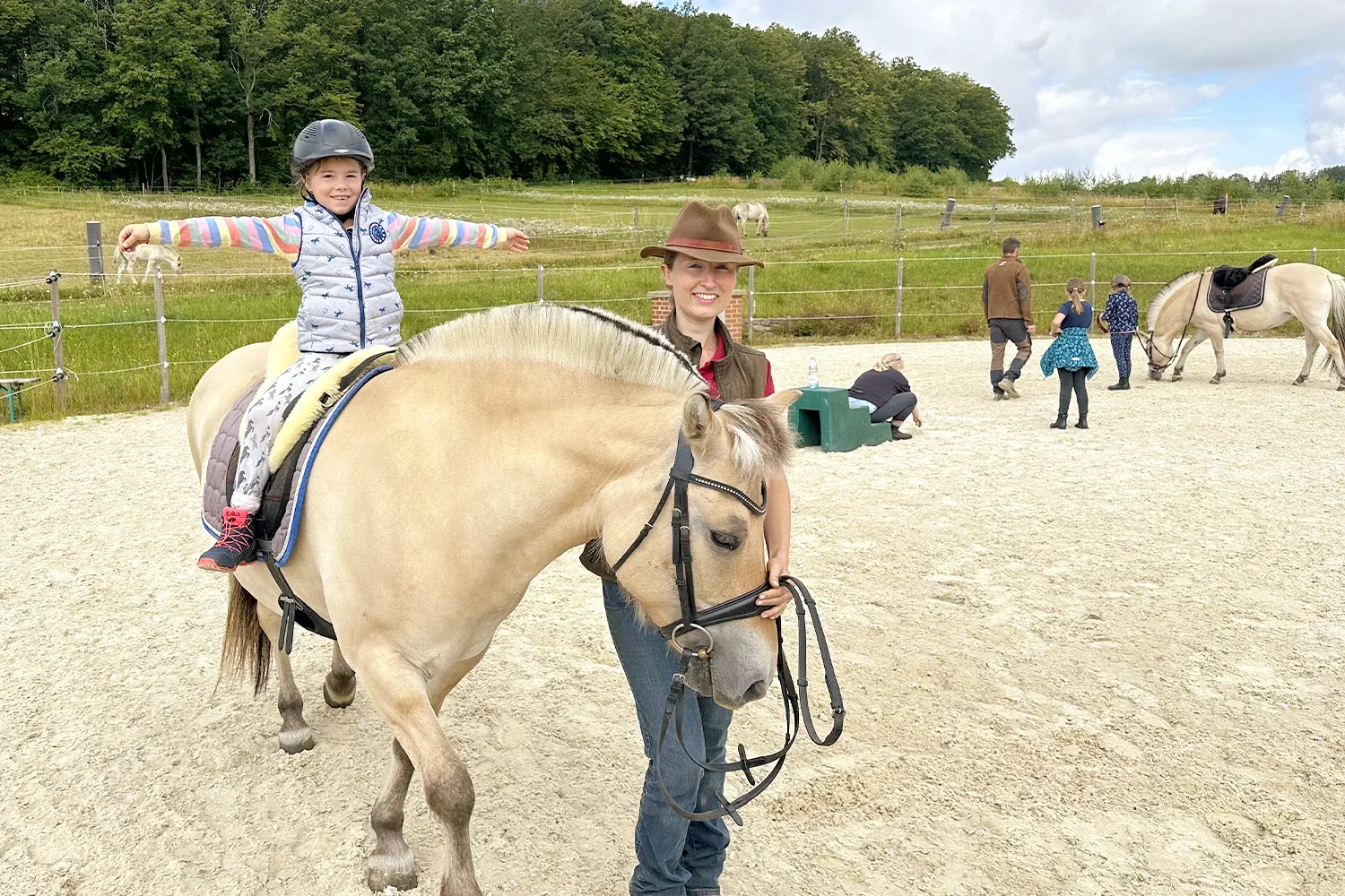 Anna-Karina Kemper führt ein Kind auf einem Fjordpferd über den Longierzirkel.